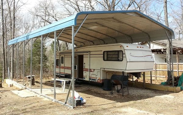 Trailer covered by a blue-roofed carport.