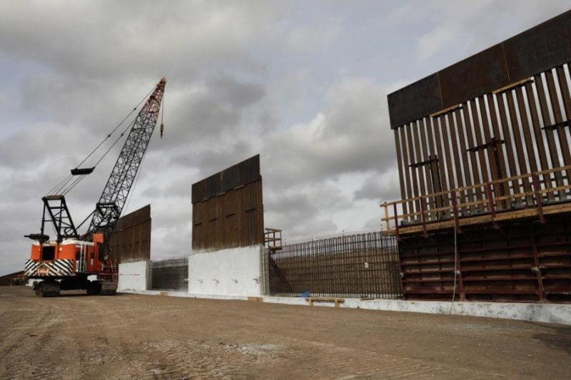 Construction crane near partially built border wall