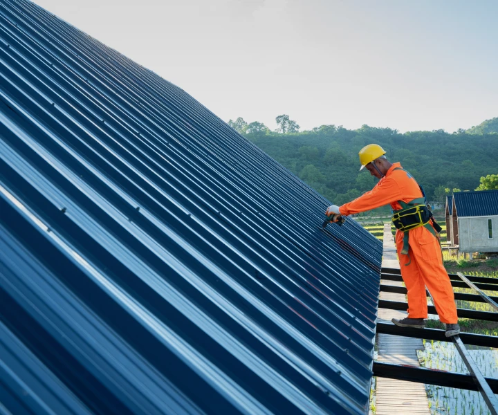 Worker installing metal roof sheets