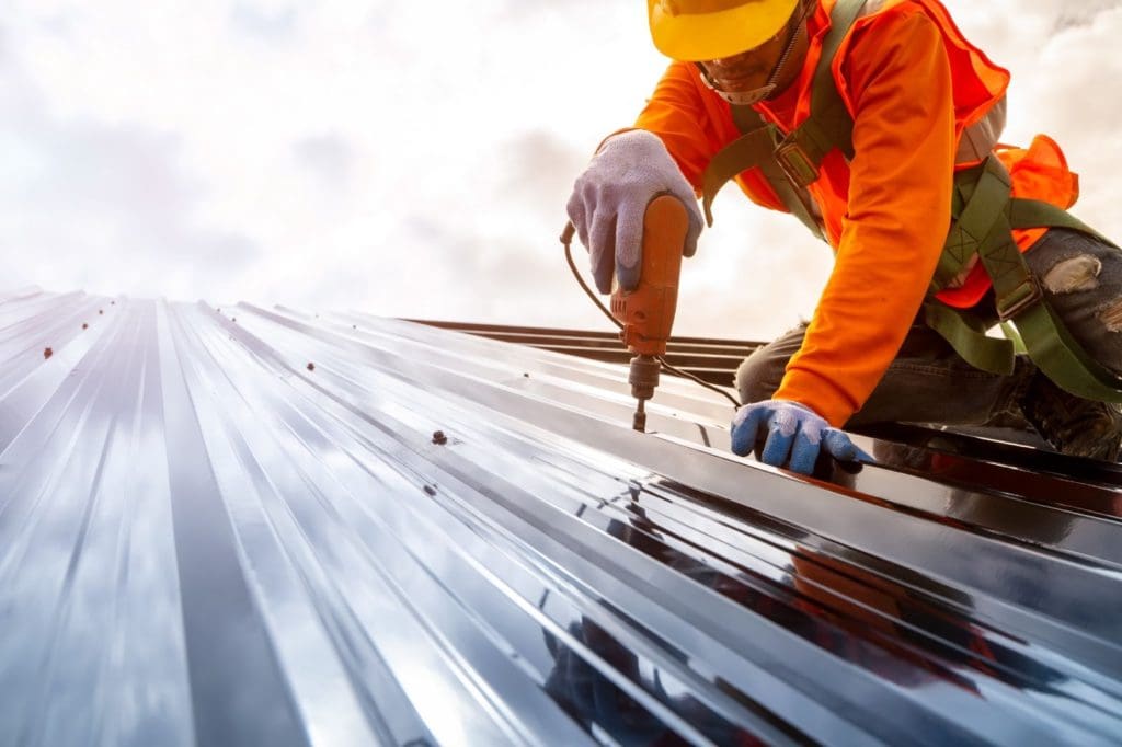 Construction worker installing metal roof panels.