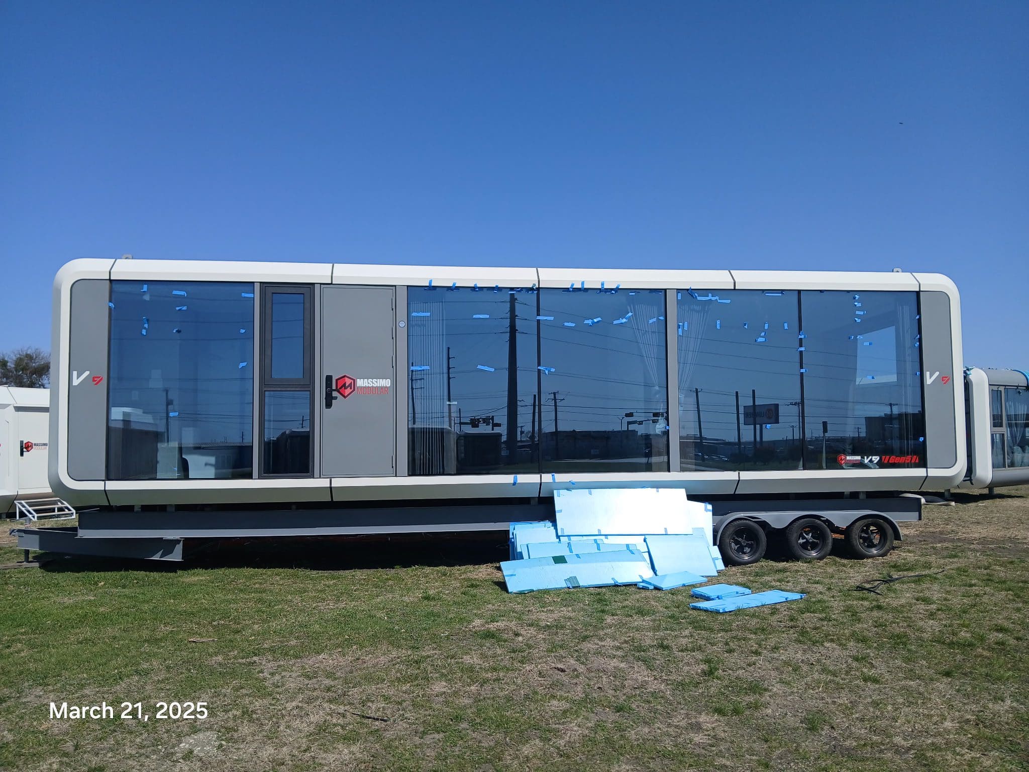 Futuristic trailer on grass under clear sky.