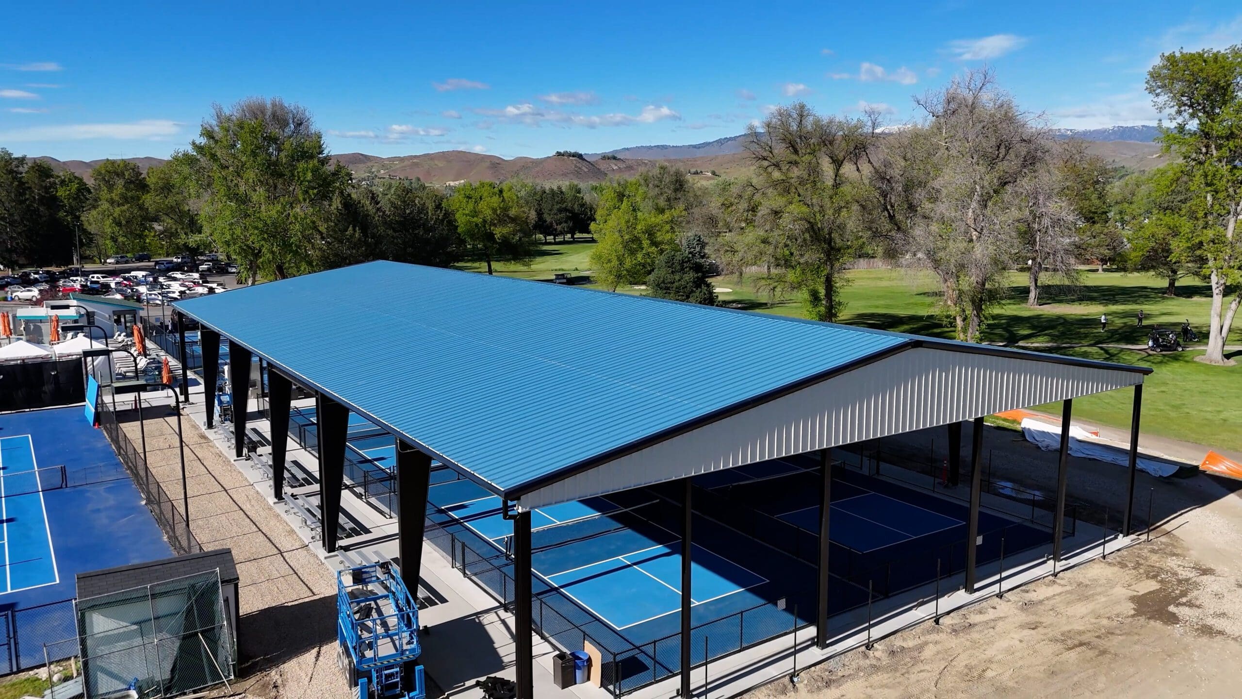 Covered outdoor sports courts with blue roof.