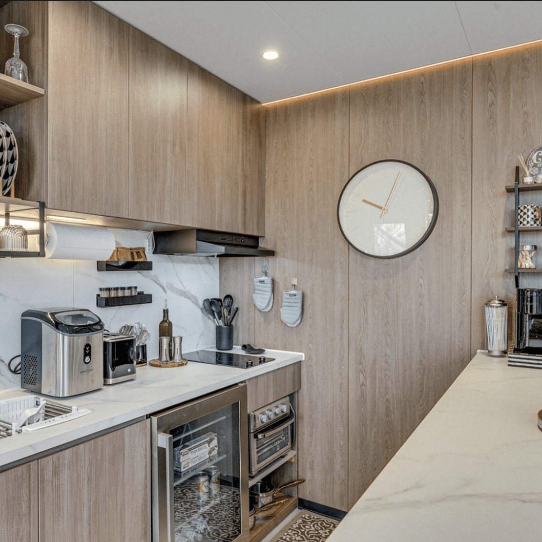 Modern kitchen with wooden cabinets and clock.