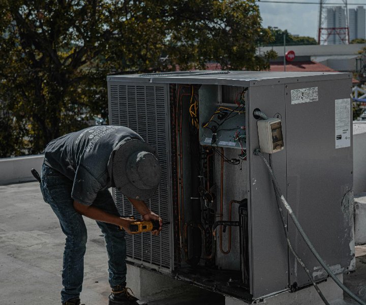 Technician repairing rooftop air conditioning unit.