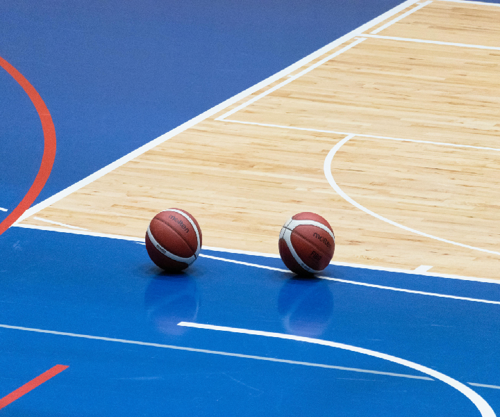 Two basketballs on a blue court.