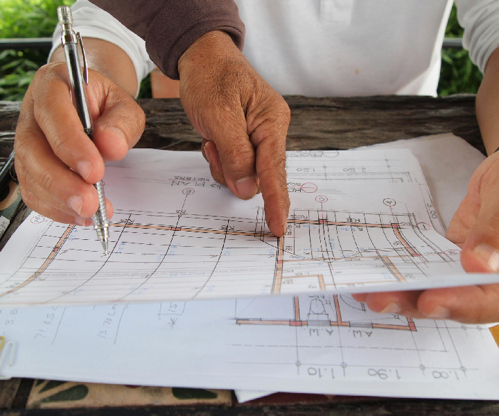 Hands reviewing architectural blueprints with pen.
