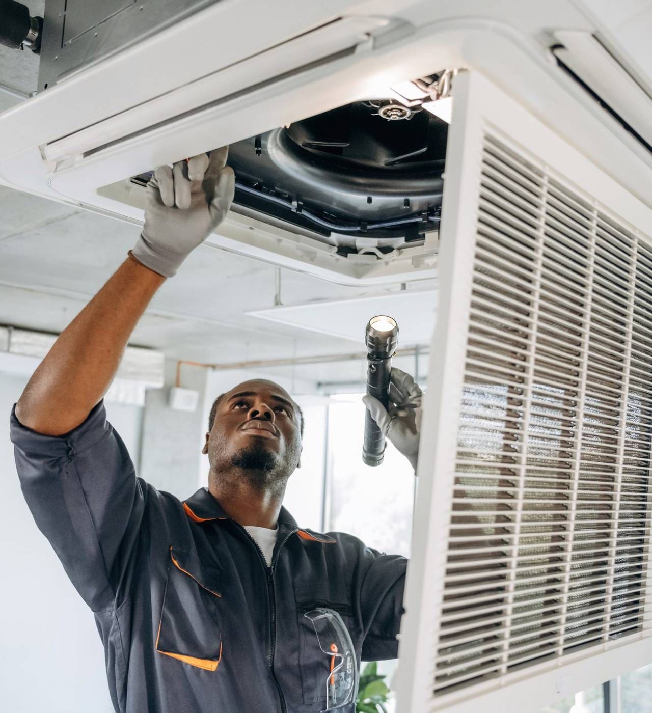Technician inspecting ceiling air conditioning unit.