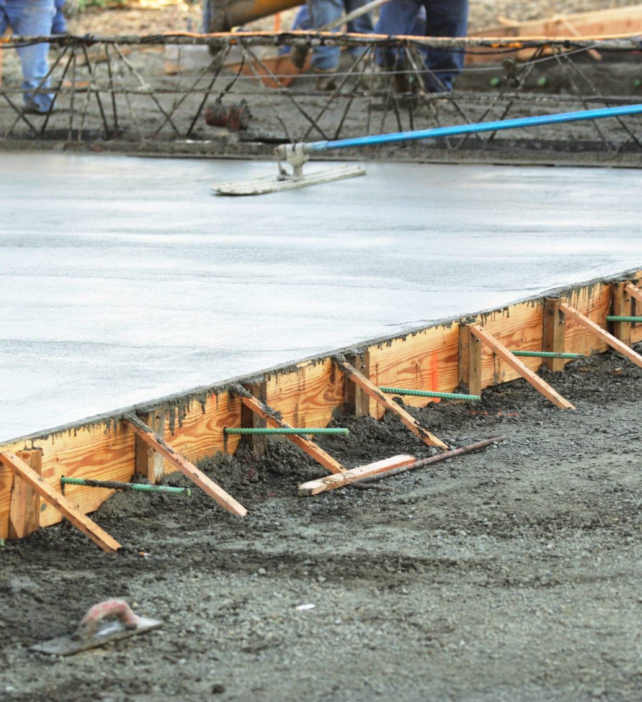 Concrete slab being smoothed at construction site.