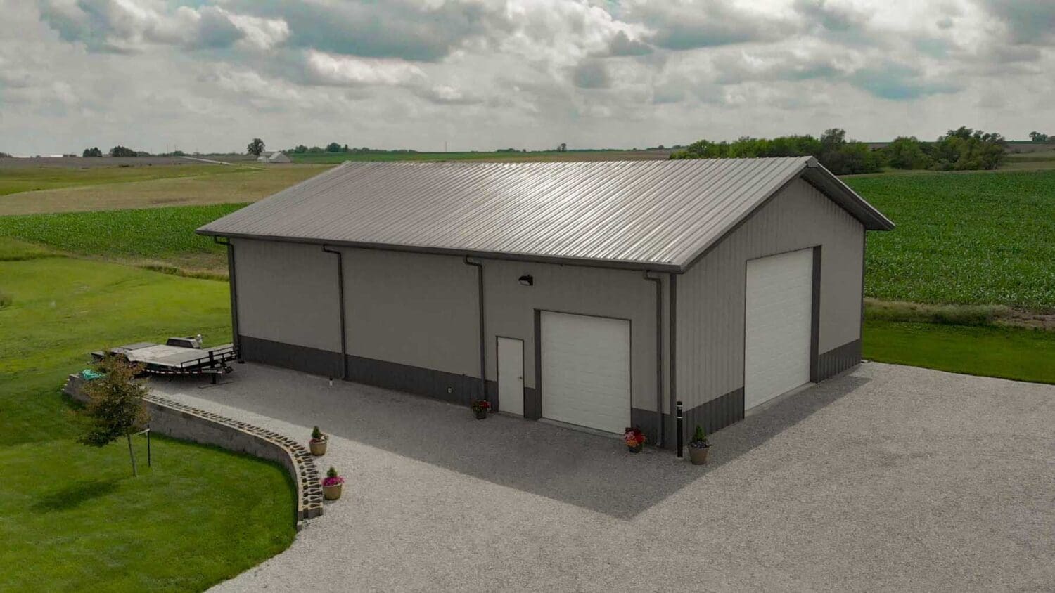 Large metal barn on a gravel lot.