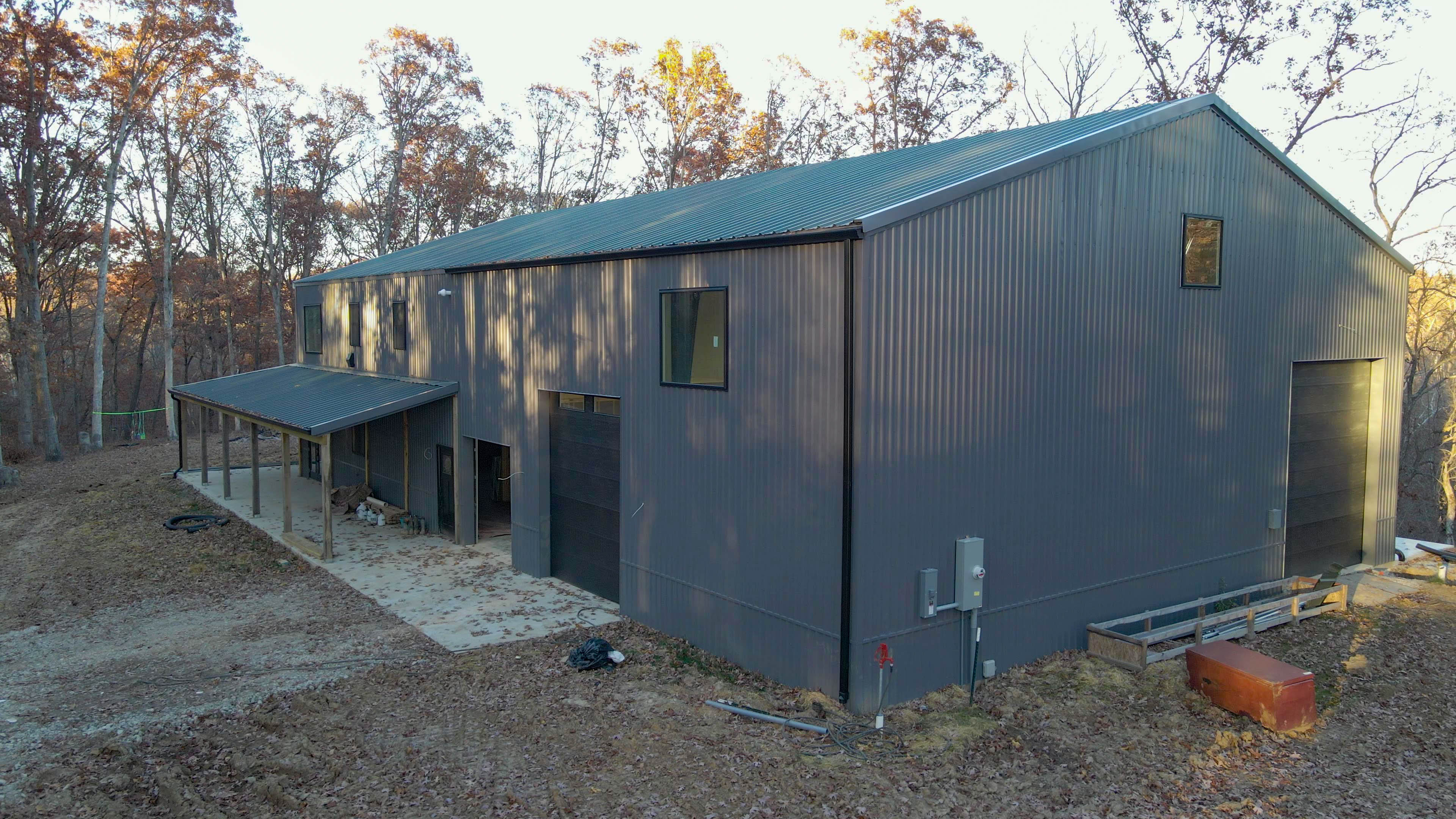 Large gray barn with surrounding trees.