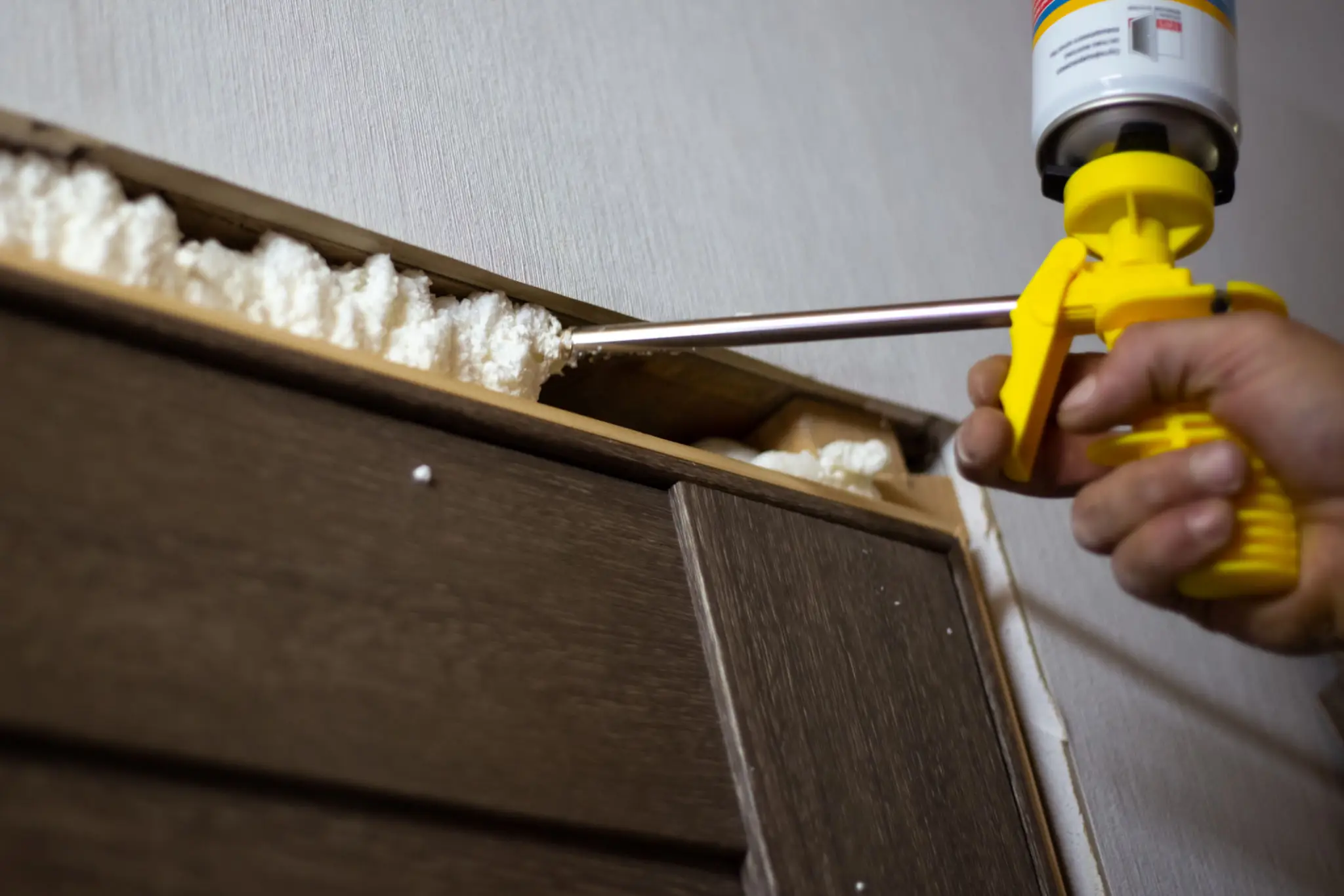 Applying spray foam insulation to wall.
