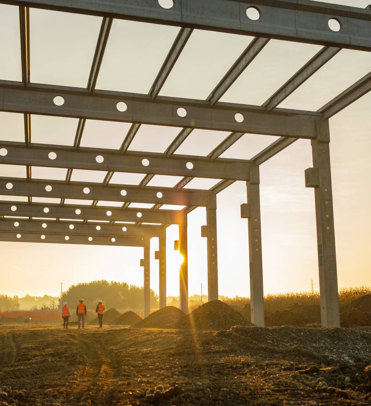 Construction site at sunrise with workers.