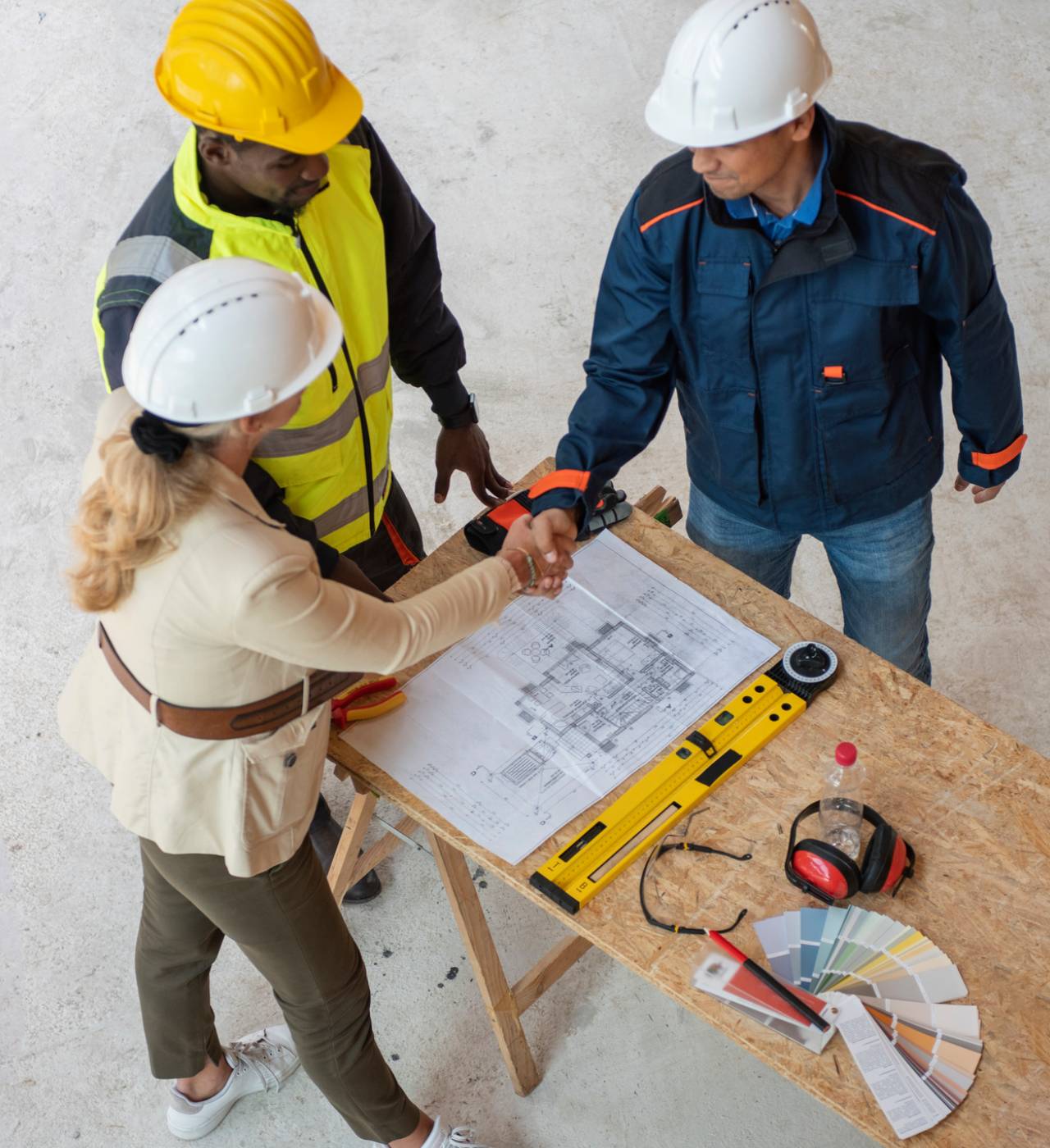 Architects shaking hands over construction plans.