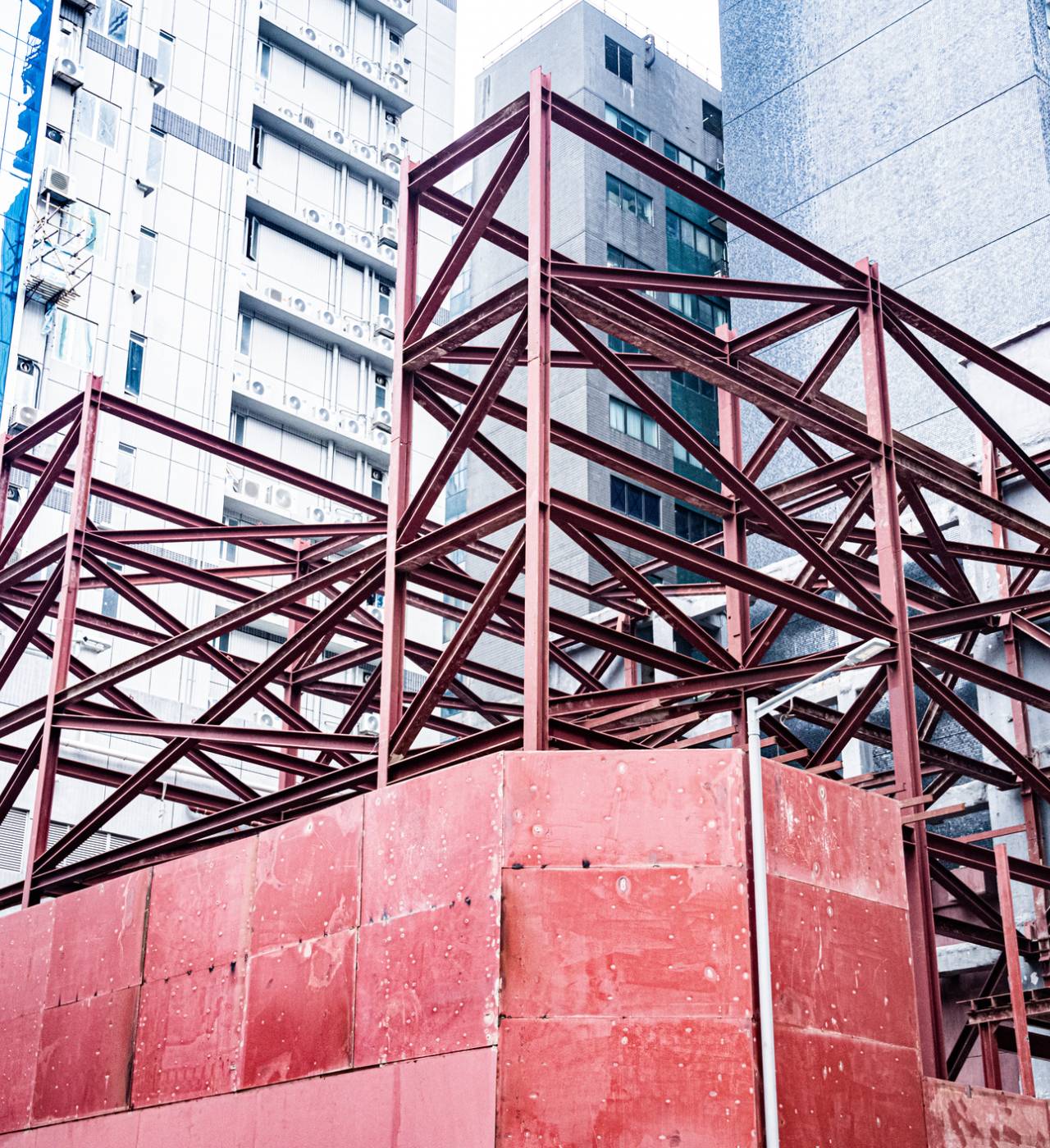 Red steel framework near tall buildings.