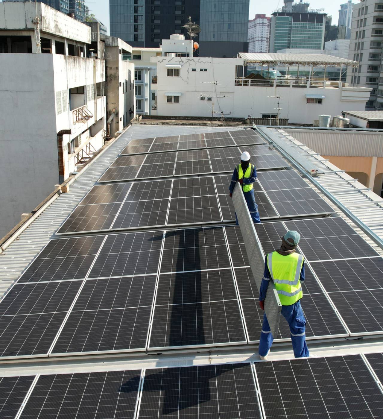 Workers installing solar panels on rooftop.