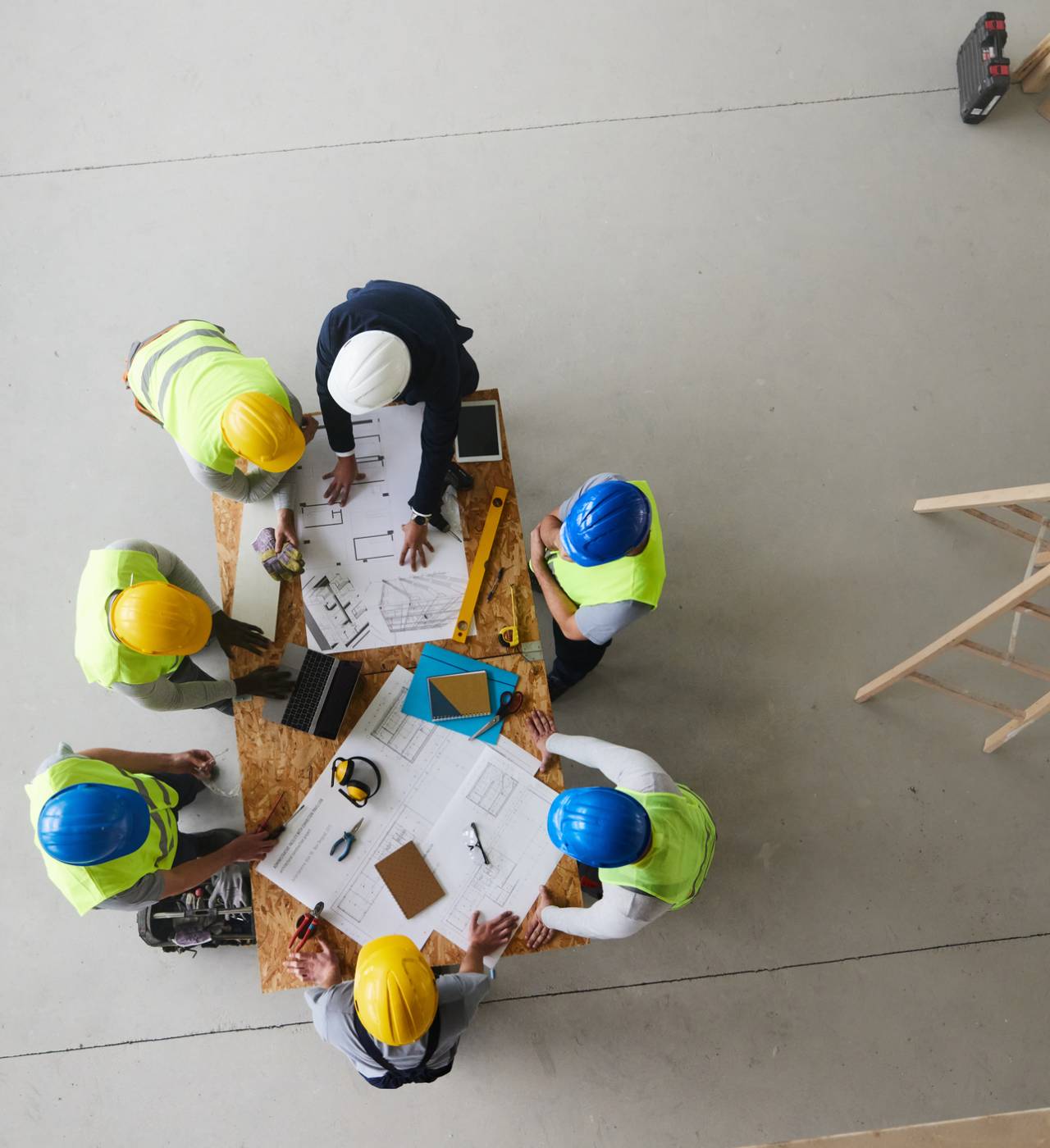 Construction team reviewing blueprints at table.