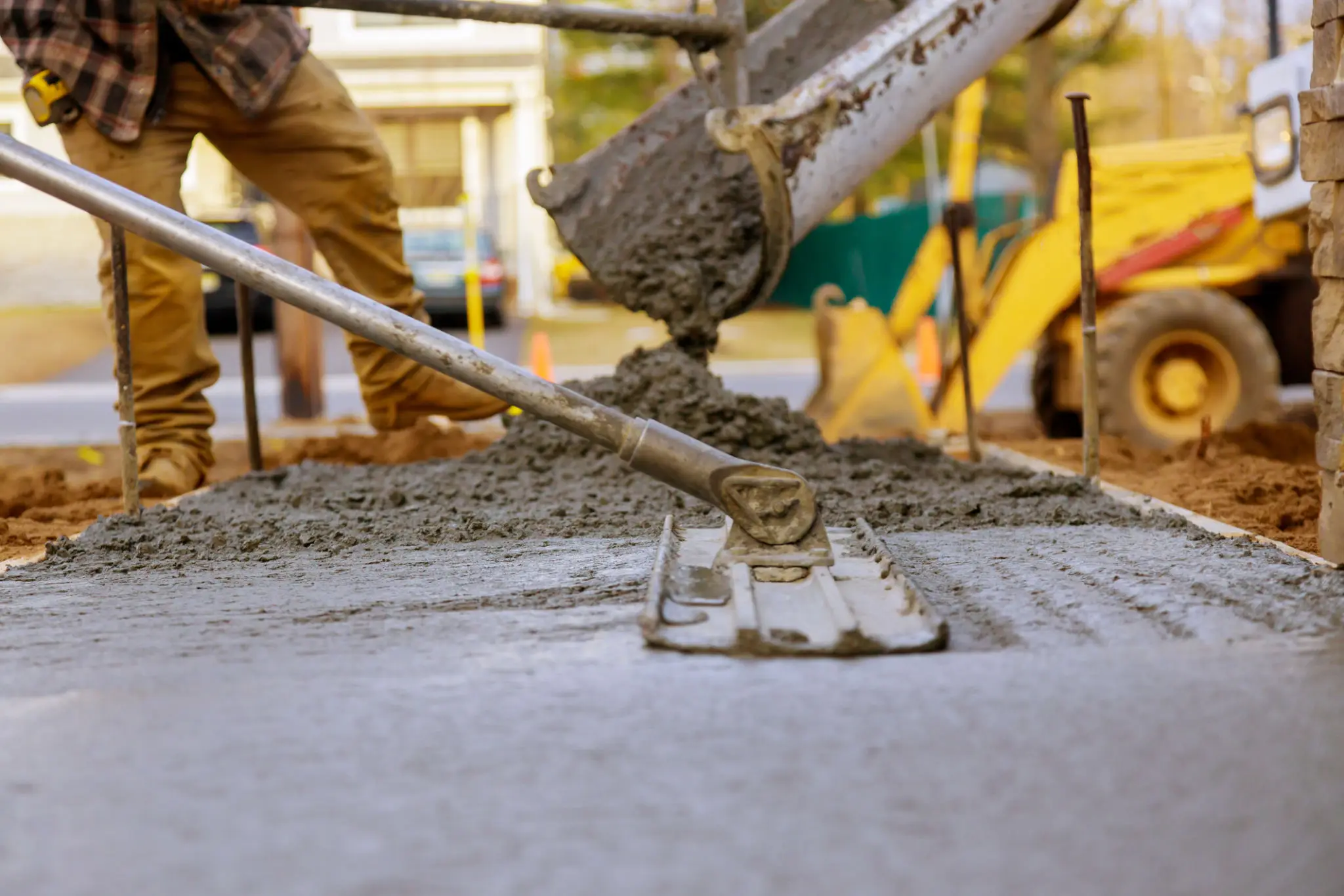 Pouring and smoothing concrete on a sidewalk.