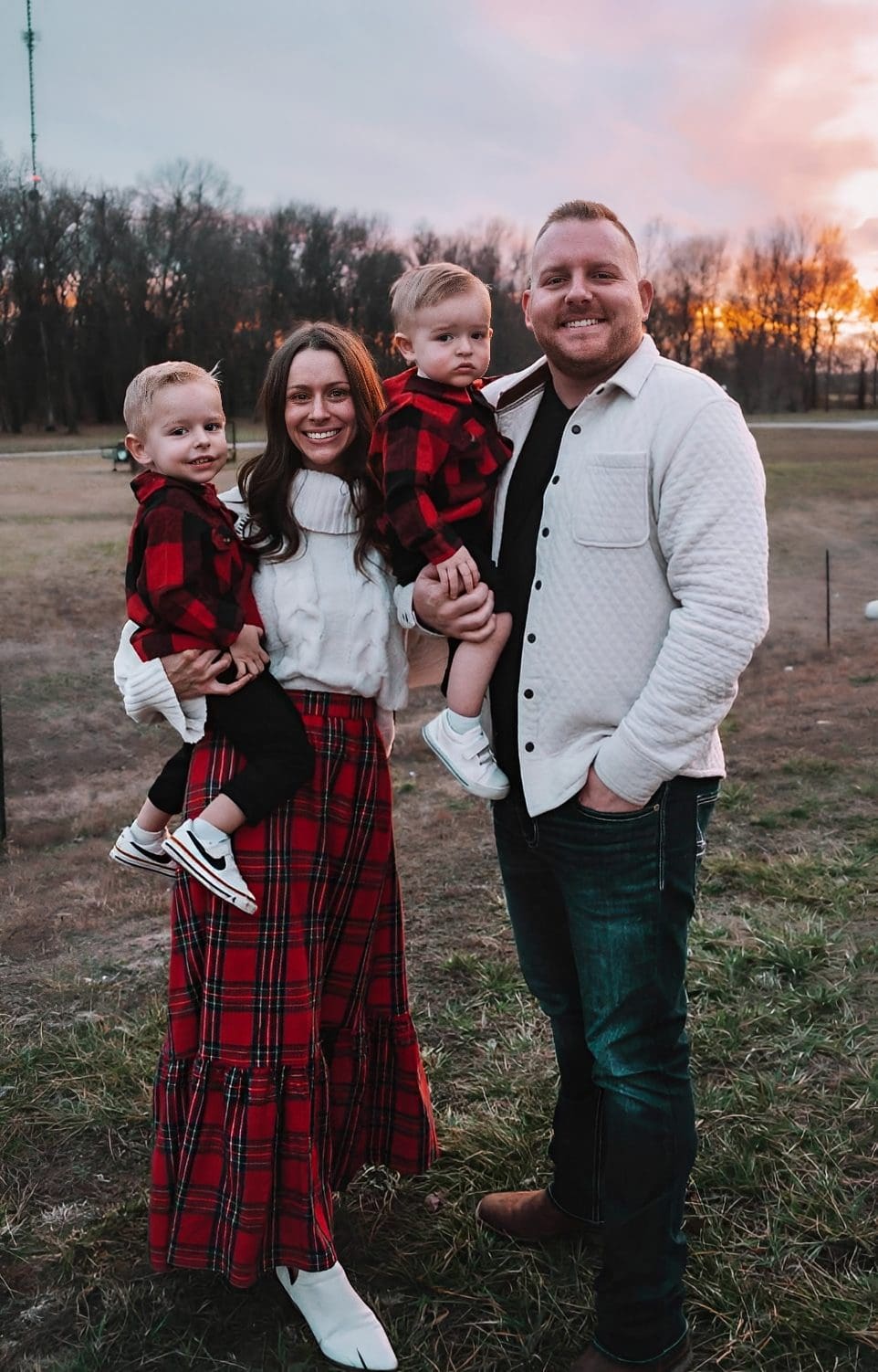 Family posing outdoors at sunset, wearing plaid.