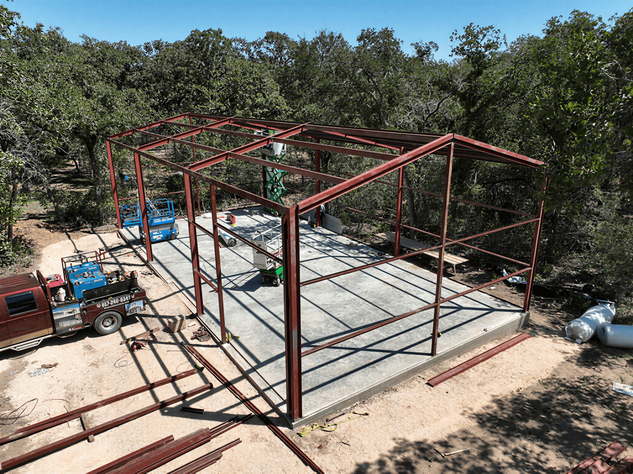 Steel structure under construction in wooded area.