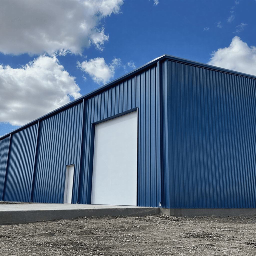 Blue industrial building under cloudy sky.