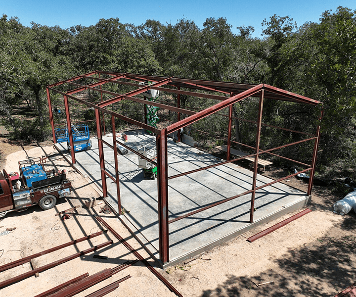 Steel building frame under construction in forest.