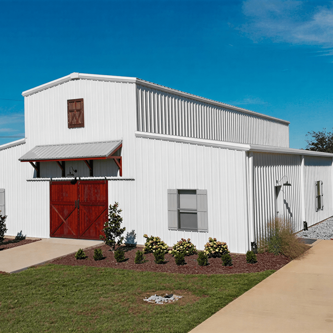 White barn with red doors, clear sky.