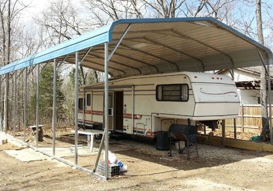 Trailer covered by a blue-roofed carport.