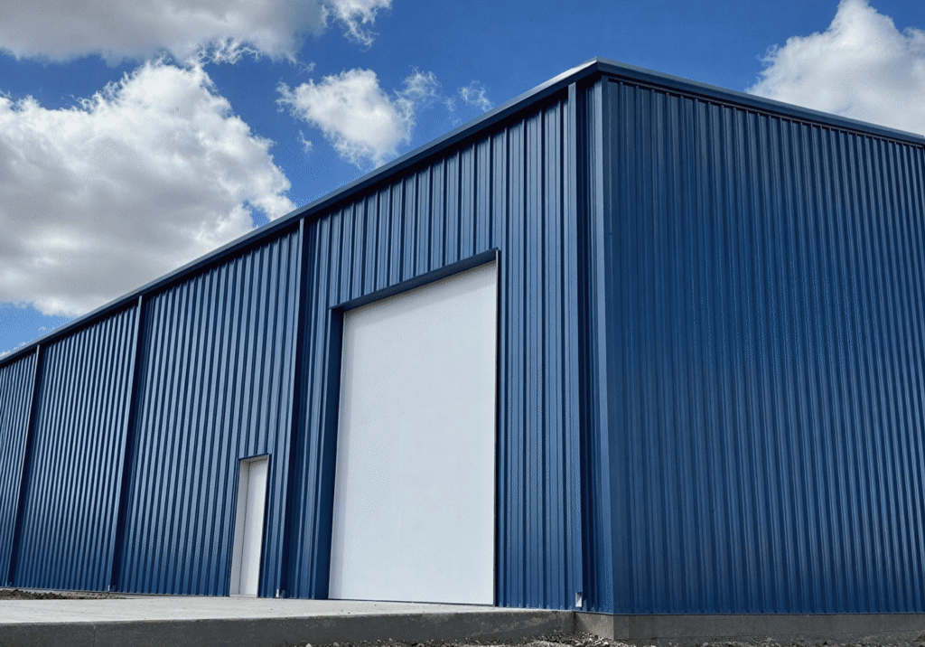 Blue industrial building under cloudy sky.