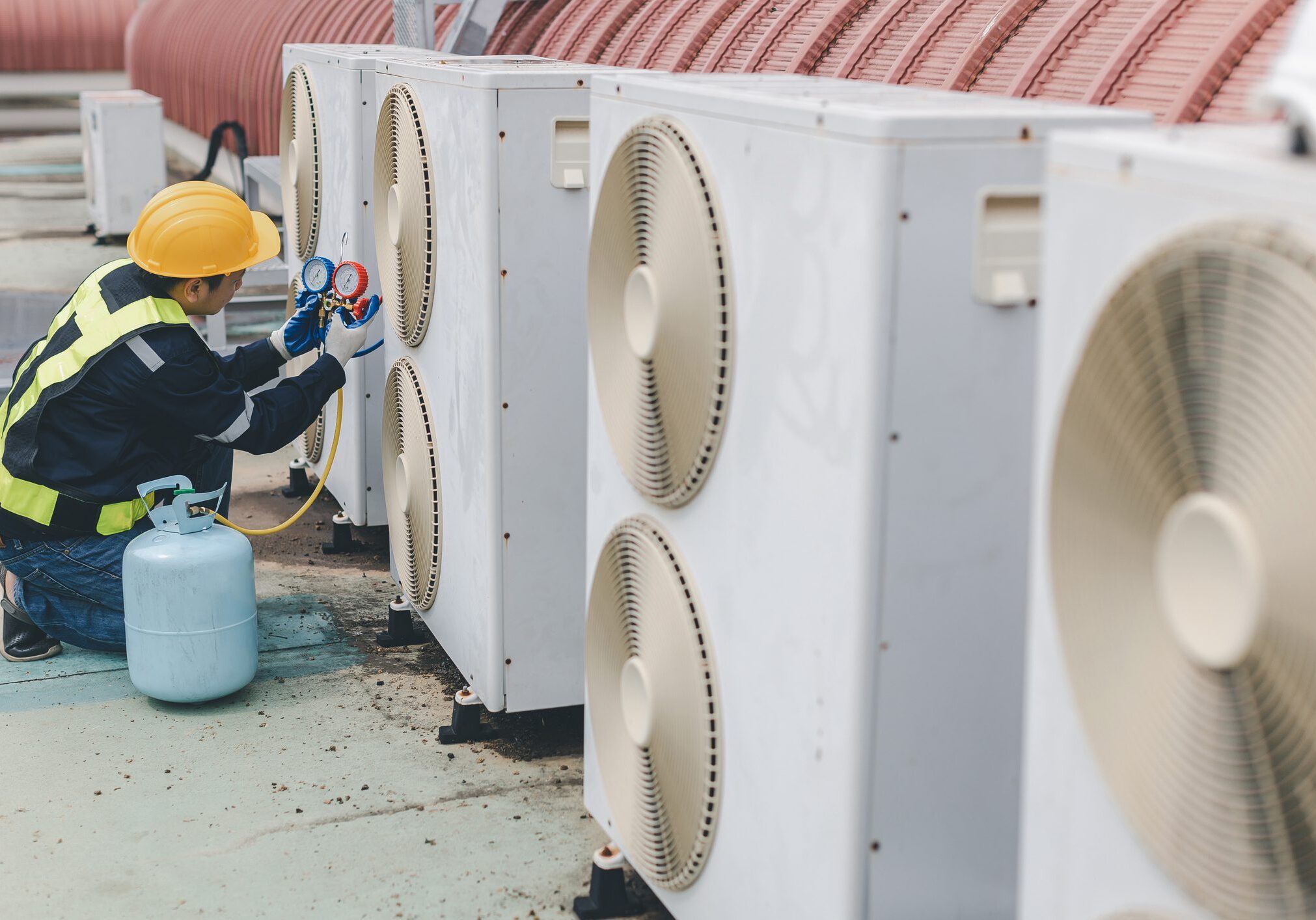 Technician servicing rooftop air conditioning units.
