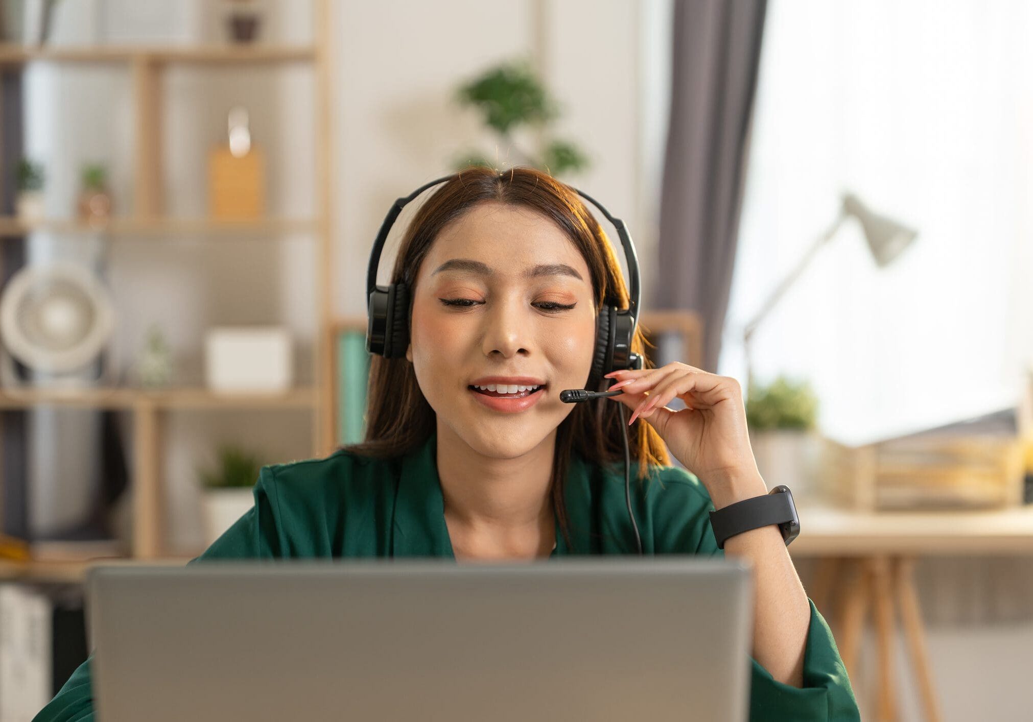 Woman with headset working on laptop.