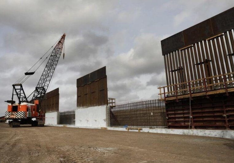 Construction crane near partially built border wall