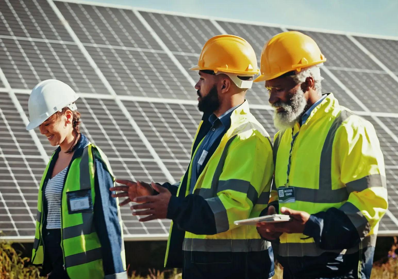 Workers discussing near large solar panel array.