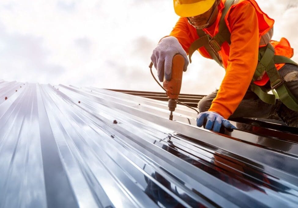 Construction worker installing metal roof panels.